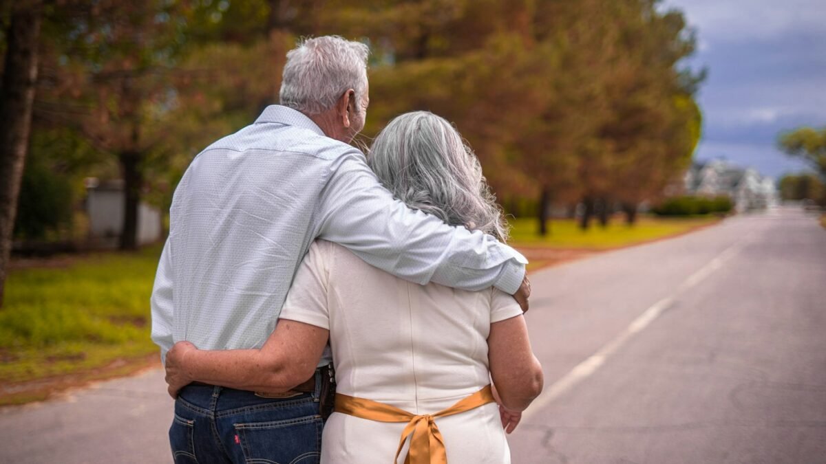 An older couple walking arm in arm outdoors. Illustrative stock photograph; they are not subjects of the article.
